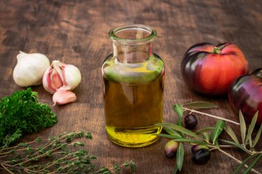 Ekstra saf zeytinyağlı bir şişe yanında domates, sarımsak ve dallarında zeytin..