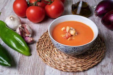 Domates, sarımsak, biber ve soğana dayalı soğuk çorba, tipik Endülüs çorbası. Beyaz ahşap arka planda.