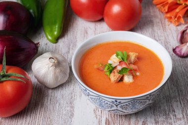 Domates, sarımsak, biber ve soğana dayalı soğuk çorba, tipik Endülüs çorbası. Beyaz ahşap arka planda.