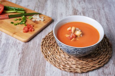 Domates, sarımsak, biber ve soğana dayalı soğuk çorba, tipik Endülüs çorbası. Beyaz ahşap arka planda.