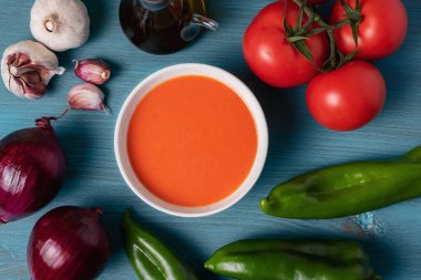 Domates, sarımsak, biber ve soğana dayalı soğuk çorba, tipik Endülüs çorbası. Mavi ahşap bir arka planda.