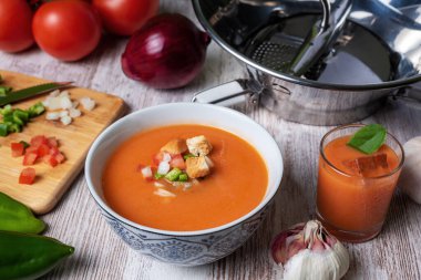 Domates, sarımsak, biber ve soğana dayalı soğuk çorba, tipik Endülüs çorbası. Beyaz ahşap arka planda.