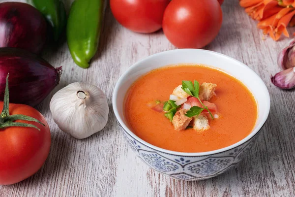 Domates, sarımsak, biber ve soğana dayalı soğuk çorba, tipik Endülüs çorbası. Beyaz ahşap arka planda.