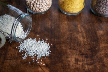 Pirinçli çömlek ahşap bir masaya saçılmış, diğer saksılarla çevrili sebzeler..