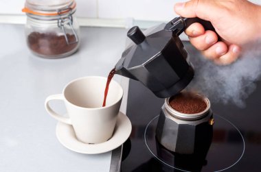 Parçalanmış kahve makinesinin bir parçası ateşte, diğeri de kahve bardağında..