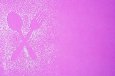 Çapraz kaşık ve çatal figürü pembe arka planda şeker rahatlatıcı oluşturuldu. 