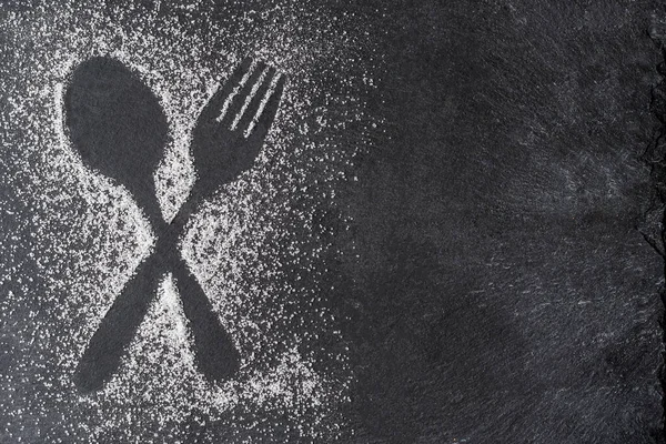 Çapraz kaşık ve çatal figürü siyah bir taş zemin üzerinde şeker rahatlatıcı oluşturuldu. 