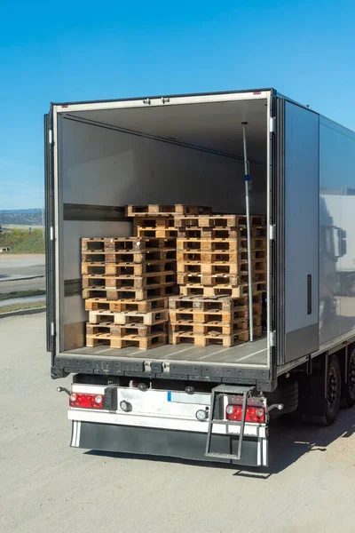 Refrigerated semi-trailer with open doors and empty Euro pallets inside.
