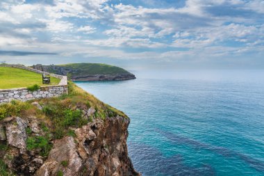 Paseo de San Pedro 'daki bankta, Llanes, Cantabrian Denizi' ndeki kayalıklara bakan.