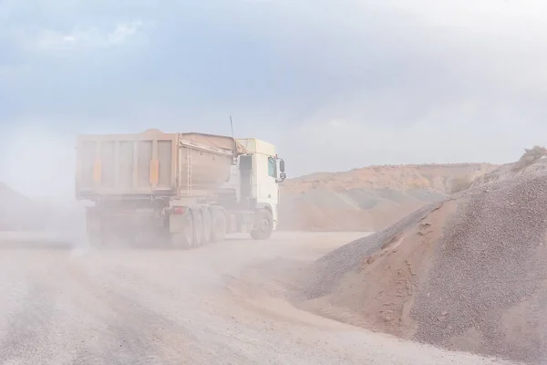 Dump truck entering a quarry to unload gravel.