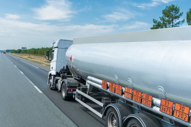 Fuel tanker truck circulating on the highway with orange panels identifying the danger and merchandise transported. clipart