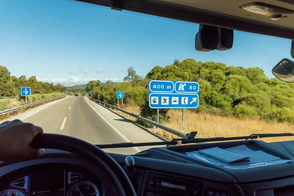 View from the driver\'s seat of a highway truck with a sign informing of a nearby service area.