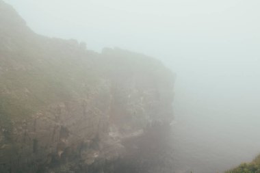 Okyanus dalgaları ve kayaların etrafındaki deniz sisi, bulutlu hava, fırtına. 