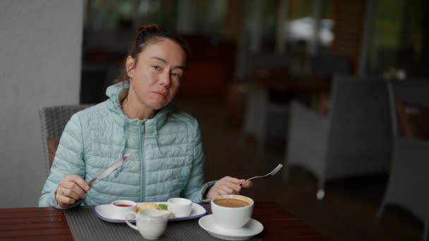 Una donna adulta fette e mangia deliziose torte al forno in un caffè. Colazione mattutina al ristorante continentale. — Video Stock