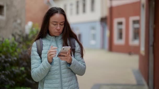 Привлекательная взрослая туристка с мобильного телефона во время прогулки по улицам старого города — стоковое видео