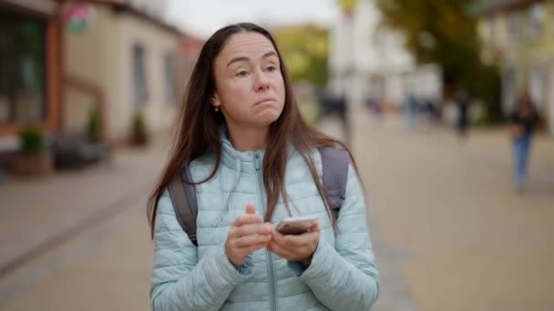 Взрослая туристка, потерявшаяся в городе во время путешествия, смотрит на дорогу по телефону — стоковое видео