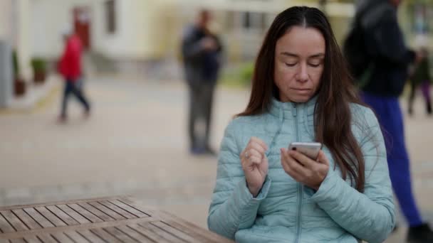 Portret szczęśliwej dorosłej kobiety piszącej na telefonie komórkowym na zewnątrz. zbliżenie na kobietę trzymającą telefon komórkowy w rękach na zewnątrz — Wideo stockowe