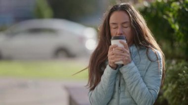 Sokaktaki üzgün orta yaşlı kadın bir fincan kahveyle kendini ısıtıyor ve gözlerini kapatıyor.