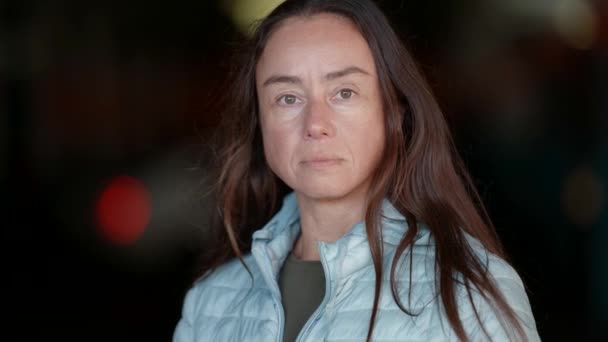 In front, a close-up portrait of an adult European woman with long hair standing on the street and looking amiably into the camera. Human face without makeup — Stock Video