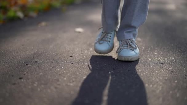 Närbild av ett kvinnligt ben när du går på väg till jobbet. En kvinna i blå gympaskor går nerför gatan. Självsäkra fötter av en flicka som går på trottoaren. — Stockvideo