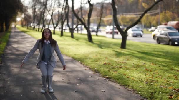 Una donna adulta attraente sta ballando mentre cammina lungo una strada della città. Saltare con la felicità in giacca e cravatta. Il concetto di emozioni. — Video Stock