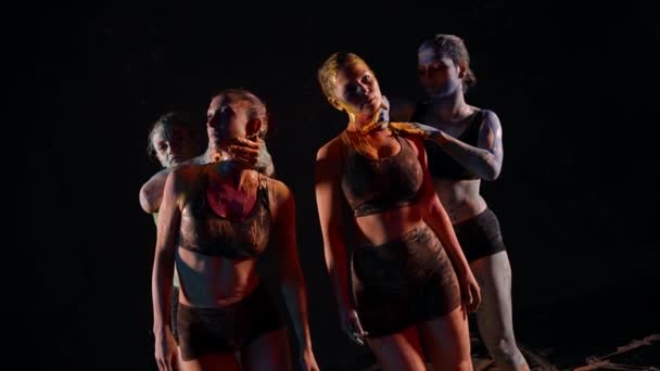 Een groep vrouwen dansend in het donker met veelkleurige verven op hun huid die een dans uitvoeren — Stockvideo