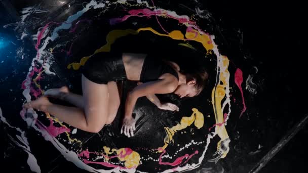 Top view of a woman lying in a circle of multicolored paint and improvisation movement art performance — Stock Video