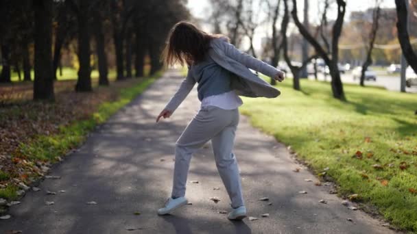 Een aantrekkelijke roodharige volwassen vrouw in een pak loopt door de stad. Het meisje lacht en geniet van de herfstdag. in slow motion. — Stockvideo