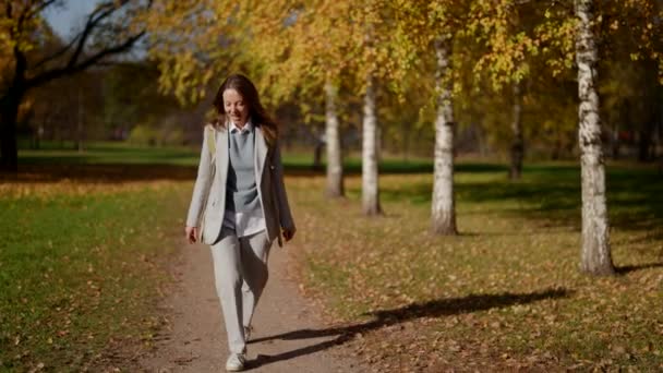 Glückliche schöne erwachsene Frau, die draußen spazieren geht. Unbekümmertes Mädchen genießt einen Herbsttag im Park — Stockvideo