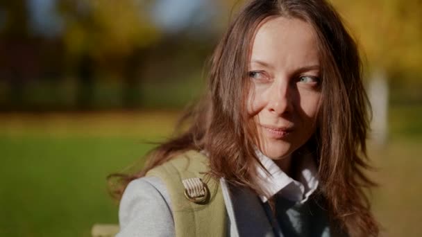 Портрет задоволеної дорослої жінки на прогулянці в міському парку вдень восени — стокове відео