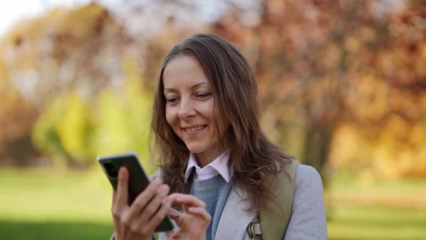 Attraktiv vuxen elegant kvinna med hjälp av sociala medier app på smartphone fjärrsamtal video, ler utomhus. Porträtt av människor. Teknik. — Stockvideo