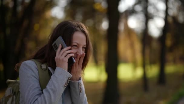 Yetişkin, neşeli bir bayan turist akıllı telefon kullanarak ailesini ve arkadaşlarını arıyor. İnsan portreleri. Teknoloji. — Stok video