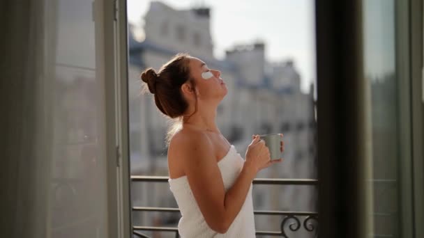 Привлекательная женщина пьет чашку кофе или чая из кружки, стоящей снаружи на балконе — стоковое видео