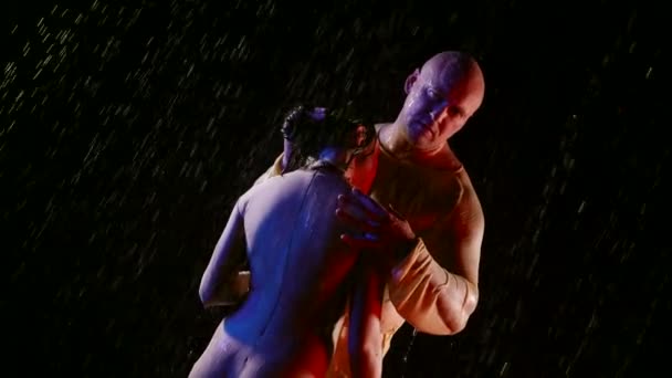 Una pareja atlética adulta abrazándose en la oscuridad bajo la lluvia. Cuerpos húmedos y musculosos. Mujer en mono mojado — Vídeos de Stock