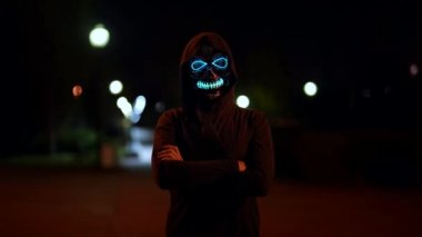 Kafatası olan maskeli bir kadın Cadılar Bayramı 'nda şehirde neon ışıklarıyla parlar.