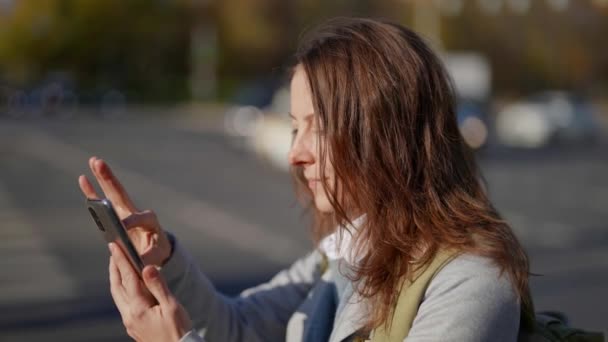 Τα πάντα φαίνεται μεγάλη πορτρέτο μιας όμορφης ενήλικης γυναίκας χρησιμοποιώντας το smartphone της, ενώ στέκεται στο δρόμο — Αρχείο Βίντεο