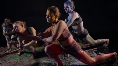 Renkli boyalarla kaplı bir grup kadın sanat performansı dansı yapıyor.