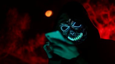 Korkunç Cadılar Bayramı canavarı iskeleti karanlıkta parlıyor cep telefonu ekranına bir mesaj yazıyor.