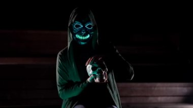 Cadı bir kadın insan kafatasını yakından tutuyor. Bir falcı bir ayin yapıyor, bir sihirbaz büyücülük için kemik kalıntılarıyla bir ayin yapıyor. Cadılar Bayramı teması, siyah bir cübbe içinde ölüm..