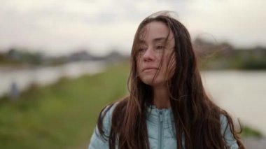 Yetişkin, güzel bir esmer rüzgârlı bir havada yürüyüş yapıyor. Saçları dalgalı, çekici bir model..