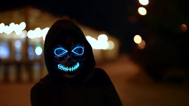 Portrait effrayant d'une femme portant un masque lumineux la nuit dans la rue — Video