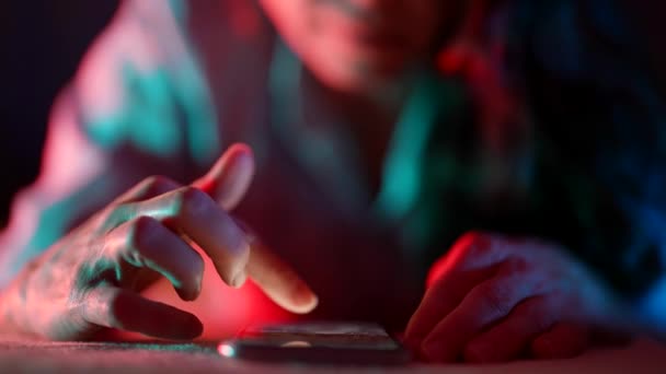 Nærbillede af kvindelige hænder, der surfer på internettet om natten i sengen. Dramatisk mørkt lys. På internettet, mobil afhængighed og søvnløshed. – Stock-video