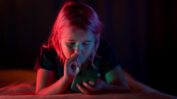 Nastolatka z różowymi włosami w nocy leżące na łóżku korzysta z telefonu do portali społecznościowych — Wideo stockowe