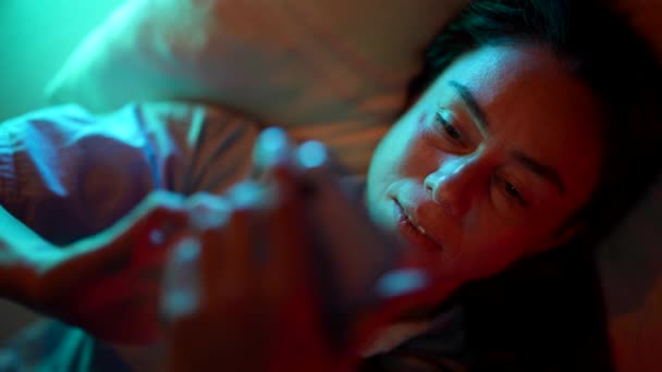 Une jolie femme adulte est allongée sur un lit la nuit souffrant d'insomnie et de dépendance à Internet — Video