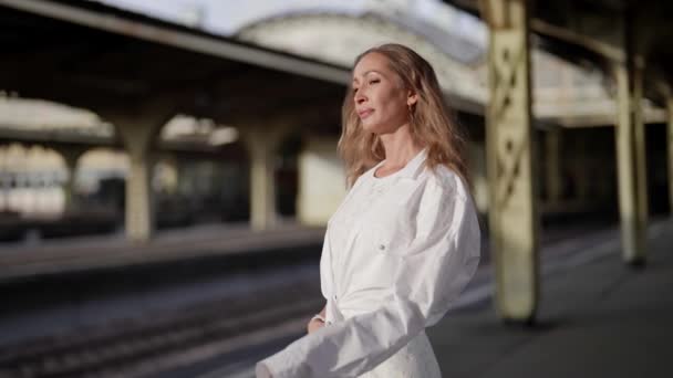 Retrato de una mujer rubia triste atractiva adulta con ropa elegante en la plataforma de la estación — Vídeo de stock