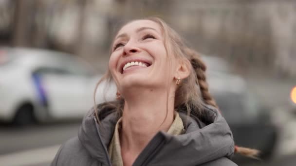 Close-up portret van een gelukkige blonde vrouw met vlechten op haar hoofd lopen rond de stad vrolijk glimlachen — Stockvideo