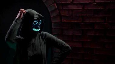 Ölüm maskesi takmış şaşırmış bir kadın Cadılar Bayramı kutlamasında eliyle başını kaşıyarak şöyle düşünür: