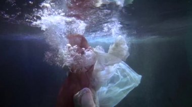 Peri masalındaki denizkızı gibi zarif bir elbiseyle suyun altında yüzen güzel bir kadın.