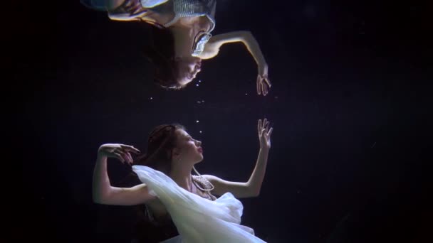 Una mujer en un vestido baila bajo el agua en ella trata de tocar su reflejo — Vídeo de stock