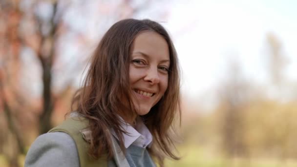 Glimlachende vrouw van middelbare leeftijd in het herfstpark, close-up portret, natuurlijke schoonheid, leeftijd-gerelateerde veranderde huid — Stockvideo